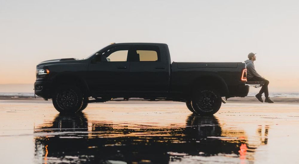 A black 2024 Ram 2500 is shown from the side near the ocean.