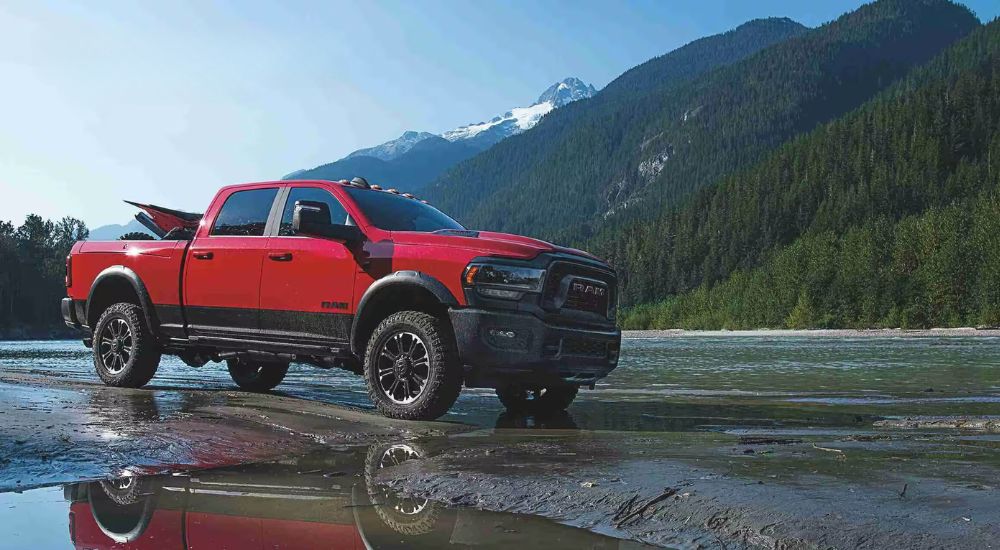 A red 2024 Ram 2500 Rebel is shown near a lake after leaving a Ram dealer.