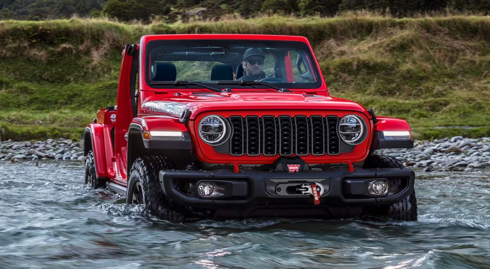 A red 2024 Jeep Wrangler Rubicon fording through a river.