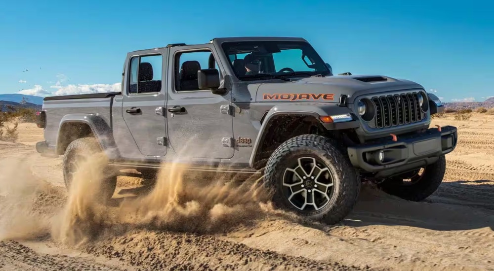 A grey 2024 Jeep Gladiator Mojave kicking up sand while off-roading.