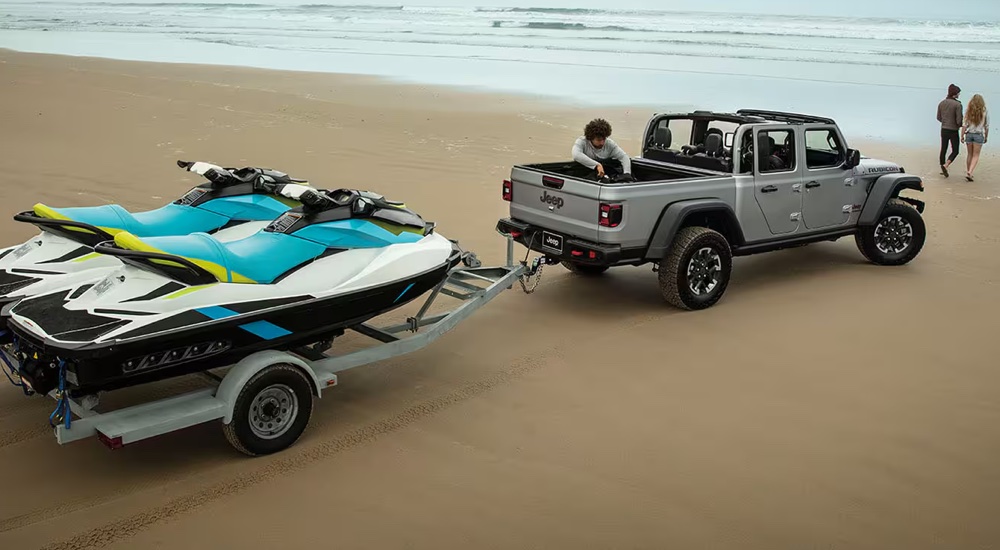 Overhead view of a grey 2024 Jeep Gladiator Rubicon towing jet skis on the beach.
