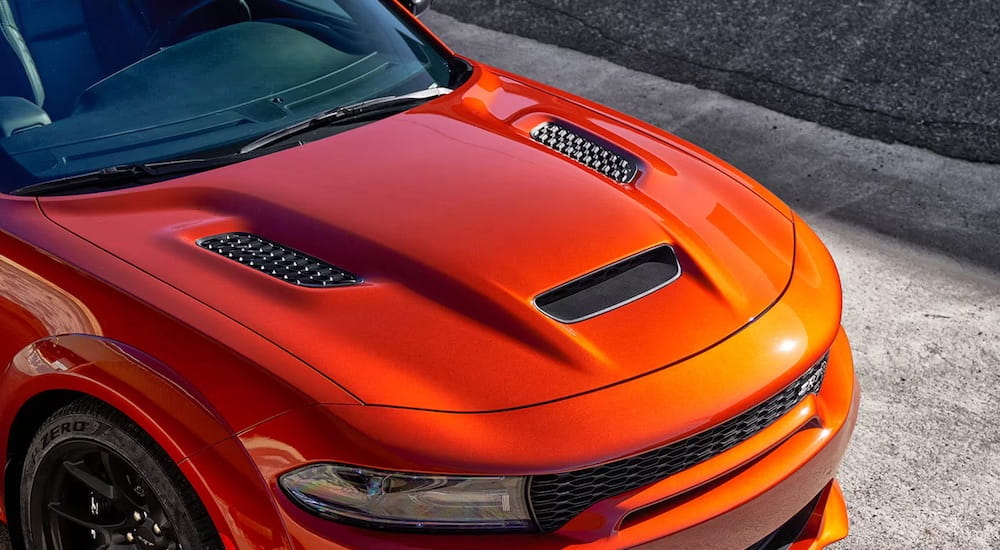 An orange 2023 Dodge Charger Hellcat is shown from the front in close-up.