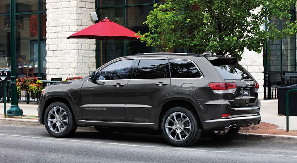 Rear angle of a black 2020 Jeep Grand Cherokee Summit parked by a used Jeep dealer.