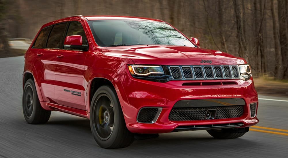 A red 2020 Jeep Grand Cherokee Trackhawk driving down a road.