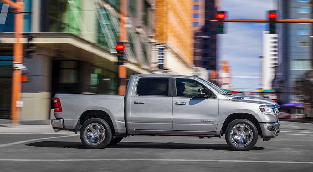 Side angle view of a silver 2019 Ram 1500 driving through an intersection.