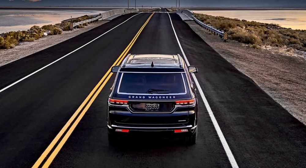 Rear overhead view of a black 2024 Jeep Grand Wagoneer L driving to a Jeep dealer.