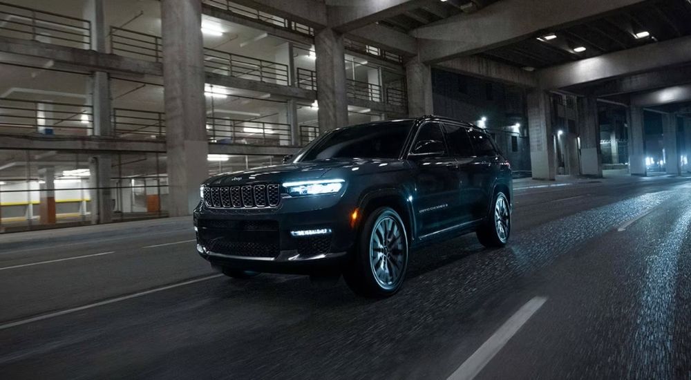 A black 2025 Jeep Grand Cherokee Summit Reserve driving at night.