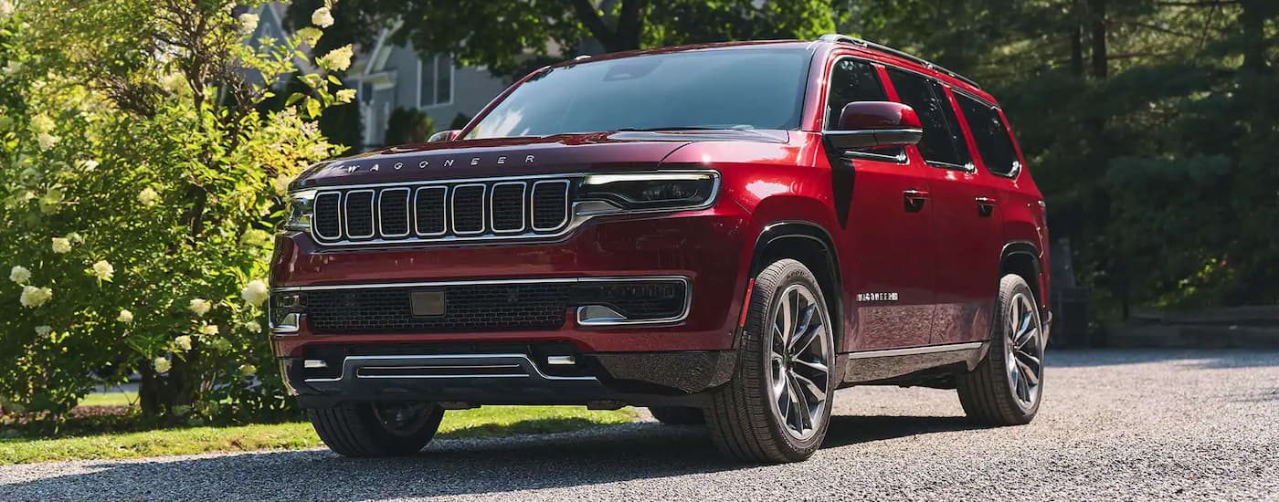 A red 2024 Jeep Wagoneer is shown parked by a Jeep dealer.