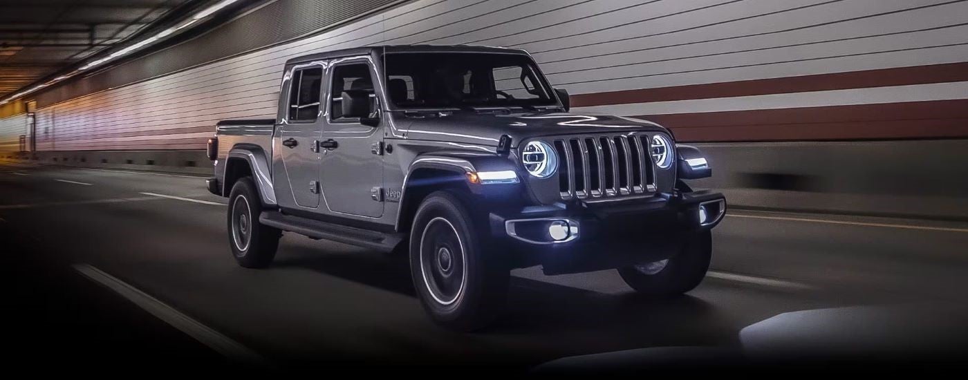 A grey 2024 Jeep Gladiator for sale driving through a tunnel.