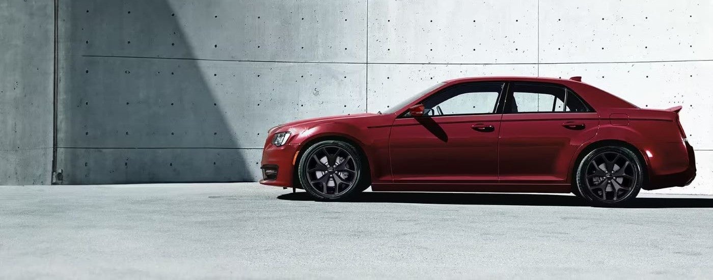 A red 2023 Chrysler 300 parked in front of a concrete wall.