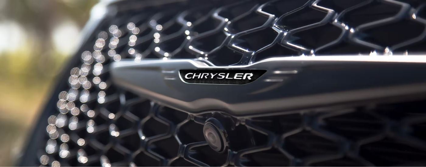 Close-up of the grille of a black 2025 Chrysler Pacifica Limited at a Chrysler dealer.