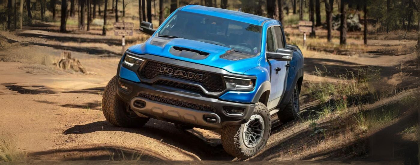 A blue 2023 Ram 1500 TRX is shown off-road after leaving a Ram dealer.
