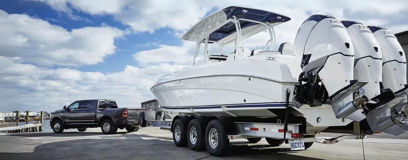 A grey 2023 Ram 3500 is shown towing a boat at a pier.