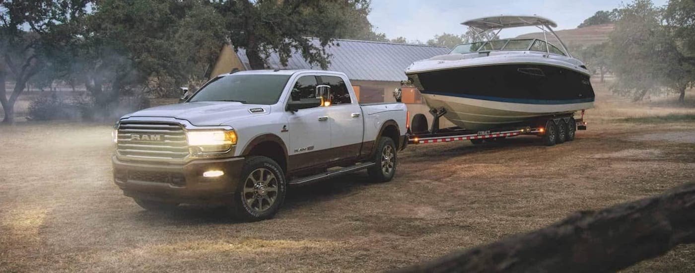 Left angled view of a white 2021 Ram 2500 towing a boat.