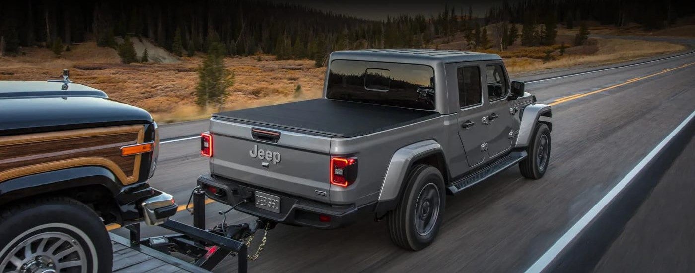 Rear view of a grey 2022 Jeep Gladiator towing another vehicle.