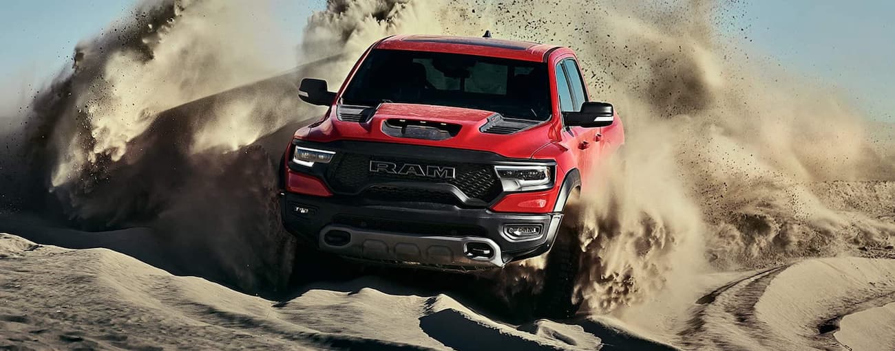 A red 2021 Ram 1500 TRX driving off-road down a dune.